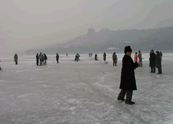 People are ice skating in the frozen lake of Summer Palace